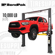 A red truck lifted on a BendPak 2-post lift with a 10,000 lb capacity, positioned at a dealership.