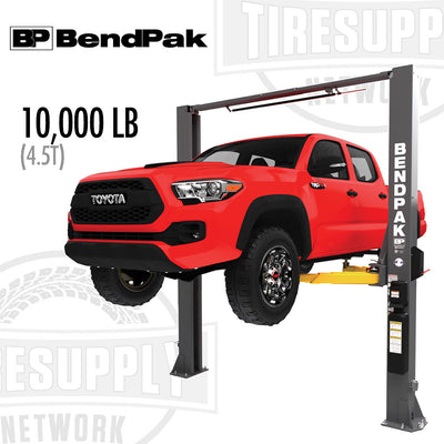 A red truck lifted on a BendPak 2-post lift with a 10,000 lb capacity, positioned at a dealership.