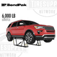 Red SUV on a BendPak tire changer with 'BP BendPak' and 'Tiresup Network' branding. 6000TLX